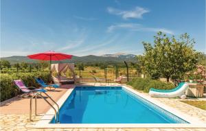a swimming pool with two chairs and an umbrella at Holiday Home Prolozac Donji 12 in Donji Proložac