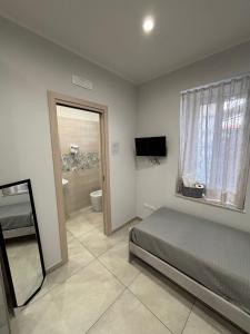 a bedroom with a bed and a television and a bathroom at La casa di Flò in Ercolano