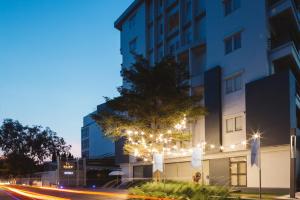 a tree with lights in front of a building at Clef Hotel Bangkok in Bangna