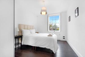 a white bedroom with a bed and a window at The Bronwen in London