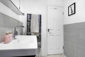a white bathroom with a sink and a mirror at The Bronwen in London +19 photos