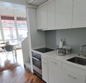 a kitchen with white cabinets and a sink and a table at Exclusive Loft in Seefeld - Mühle in Zurich
