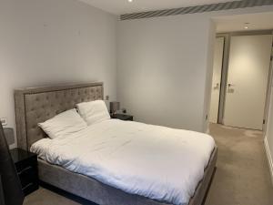 a bedroom with a large bed with white sheets at Stylish 2 Bed Flats Near US Embassy in London +5 photos