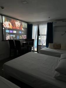 Studio w projector Wifi Netflix and pool access in ADB Tower Ortigas CBD في مانيلا: غرفة فندقية بسريرين وتلفزيون