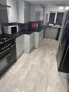 a kitchen with black and white appliances and a tile floor at Cosy rooms near Gatwick Airport in Ifield +59 photos