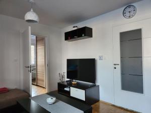 een woonkamer met een tv en een klok aan de muur bij RingPeace Apartment, Trnsko in Zagreb