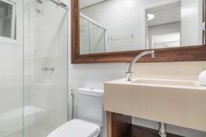a bathroom with a toilet and a sink and a mirror at Loft central para família by Achei Gramado in Gramado +18 photos
