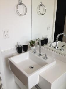 a white sink in a bathroom with two mirrors at Estúdio Vila Madalena in Sao Paulo