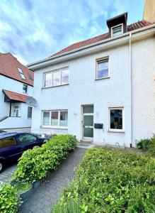 a white house with a car parked in front of it at Design Apartment im Zentrum von Nienburg! in Nienburg