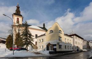 a large white building with a clock tower and a church at Number 5 Vlevo Dole in Rokytnice nad Jizerou