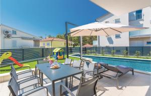 a patio with tables and chairs next to a pool at Amazing Home In Biograd With Kitchen in Biograd na Moru