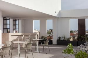 a rooftop patio with tables and chairs and windows at Alinea Suites Limassol Center in Limassol