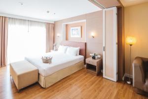 a hotel room with a large bed and a window at Clef Hotel Bangkok in Bangna