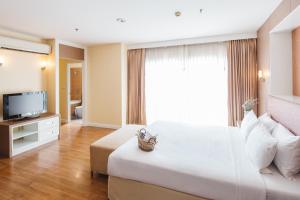 a bedroom with a large white bed and a television at Clef Hotel Bangkok in Bangna +55 photos