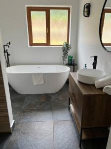 5-bed house near Rathmullan beach في راثمولان: حمام مع حوض استحمام كبير ومغسلة