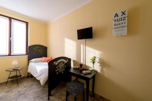 Schlafzimmer mit einem Bett, einem Schreibtisch und einem TV in der Unterkunft B&B Il Riccio in Tirano
