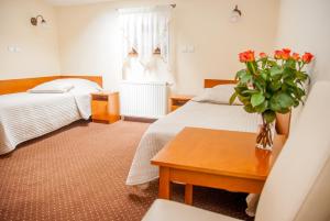 a hotel room with two beds and a vase of flowers on a table at U Pana Cogito in Krakow