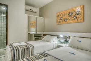 a hotel room with two beds and a mirror at Hotel Pousada Da Sereia in Maceió