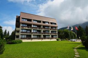 un edificio con un césped verde delante de él en Ferienwohnungen Chesa Clois 24, en Lenzerheide