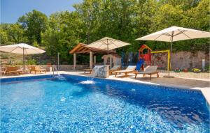 basen z 2 parasolami i krzesłami w obiekcie Four-Bedroom Holiday Home In Grubine w mieście Grubine
