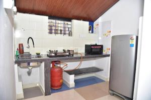 a kitchen with a stove and a refrigerator at Blue Bell Homestay in Udupi