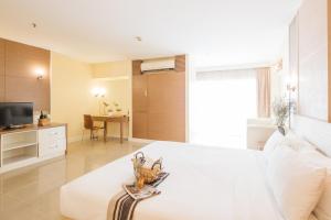 a living room with a white bed and a television at Clef Hotel Bangkok in Bangna