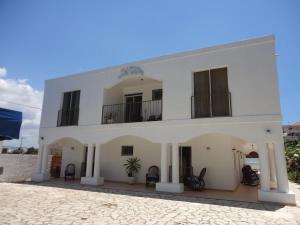 a white building with chairs in front of it at Hotel Angel Gabriel in Boca Chica
