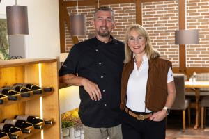 a man and a woman standing in a room with wine bottles at Hotel Forsthaus in Winterberg