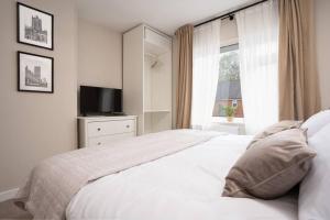 Un dormitorio con una cama blanca y un televisor. en Three Bedroom House by Brookland Stays Serviced Accommodation Short Lets Manchester with Free WiFi, en Mánchester