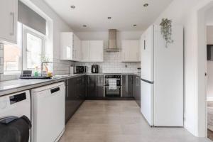 Una cocina con gabinetes blancos y un refrigerador blanco. en Three Bedroom House by Brookland Stays Serviced Accommodation Short Lets Manchester with Free WiFi, en Mánchester