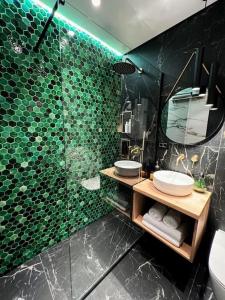 a bathroom with a green tiled wall with a mirror at Studio 7- A chic urban hideaway, 10min walk to city center in Timişoara +30 photos