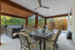un porche grillagé avec un barbecue, une table et des chaises dans l'établissement 3 Mi to Lake Cabin with Hot Tub in Broken Bow!, à Stephens Gap