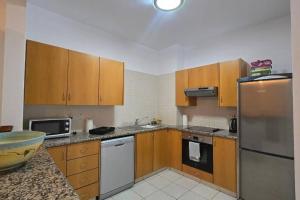 a kitchen with wooden cabinets and a stainless steel refrigerator at Hesperides gardens, spacious 2 bedroom apartment in Paphos