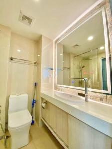 a bathroom with a toilet and a sink and a mirror at Olympus City Garden 1 Bedroom in Pattaya South