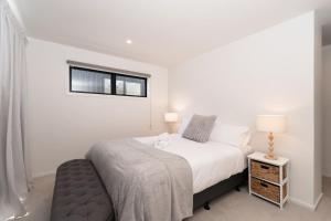 a white bedroom with a bed and a window at Amazing Retreat in Queenstown in Frankton Wharf