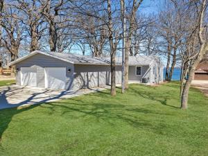 a white house with trees in front of a yard at Grassy Knoll Retreat on the Big Spirit Lake in Orleans