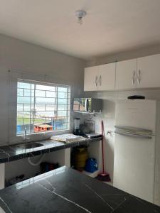 a kitchen with white cabinets and a white refrigerator at PÉ NA AREIA Apto Vicenzo in Itapoa