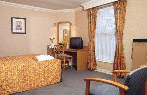 a hotel room with a bed and a desk and a window at Preston Park Hotel in Brighton & Hove