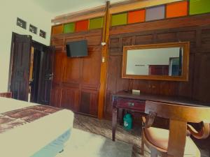 a bedroom with a bed and a desk and a mirror at Omah Adem Homestay in Ngabean +53 photos