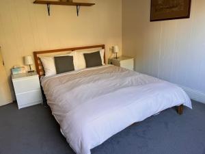 Un dormitorio con una gran cama blanca con dos mesitas de noche. en Alkira Cottage - Cozy, Comfortable, and Convenient, en Katoomba