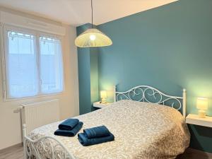 Un dormitorio con una cama con dos toallas azules encima. en Family's Home, en Bayeux