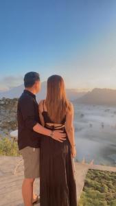 a man and a woman standing next to each other looking at the view at jungle camping in Baturaja