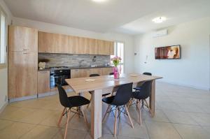 a kitchen with a wooden table and black chairs at Villetta Bianca in Scicli