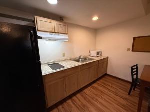 a kitchen with a sink and a black refrigerator at Relax Inn & Suites in Mattoon