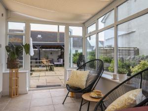 a screened in porch with chairs and a table at Trearddur View in Holyhead