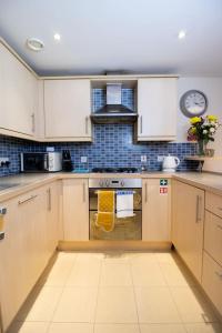 a kitchen with white cabinets and a stove top oven at Brunel Apartment, Sleeps 4, 2 Bedrooms, Free parking, Long stay disc in Swindon