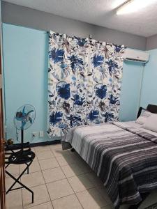 ein Schlafzimmer mit einem Bett und einer blau-weißen Wand in der Unterkunft Alexander's Place in Roseau