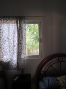 a bedroom with a window and a bed and a lamp at La bamba surf house in Dolores Miramar