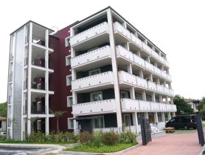 un edificio de apartamentos con balcones blancos en un aparcamiento en Guest House Residence Malpensa en Case Nuove