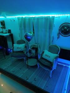 a room with two chairs and a table with a blue light at L'histoire de l'ouest , jacuzzi appartement in Dole